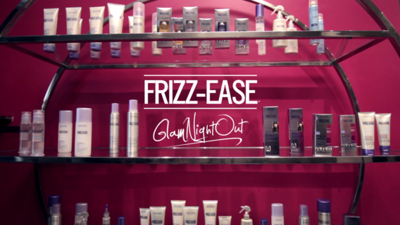 "Frizz-Ease Glam Night Out" is imposed over top of a shelf of John Freida hair products.